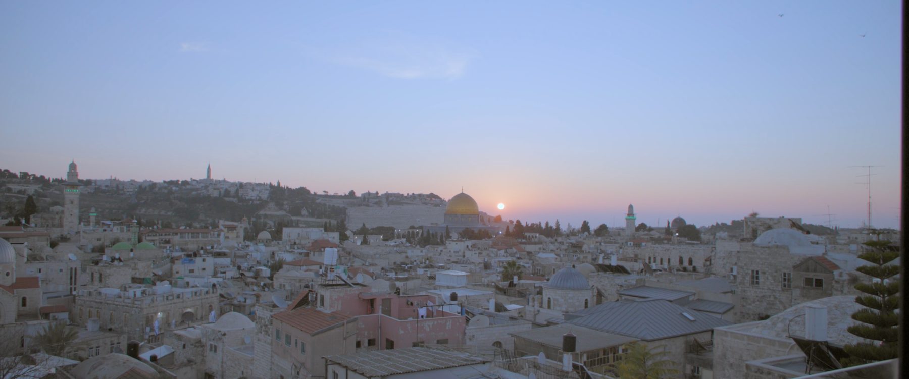 The sun setting over the Old City of Jerusalem, the Dome of the Rock catching the last light